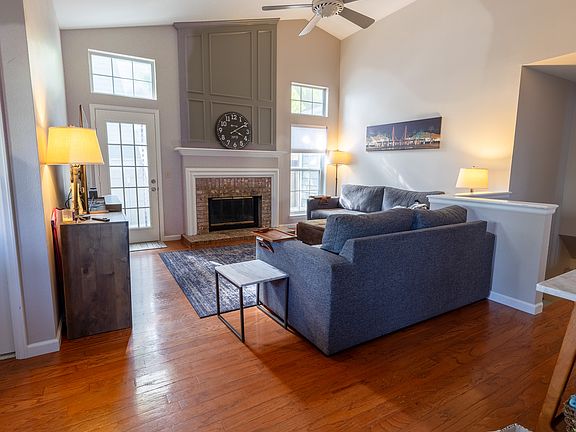 A space to gather, unwind, and connect_sunlit family room with wood floors, a cozy gas fireplace, and easy access to the patio for effortless indoor-outdoor living.