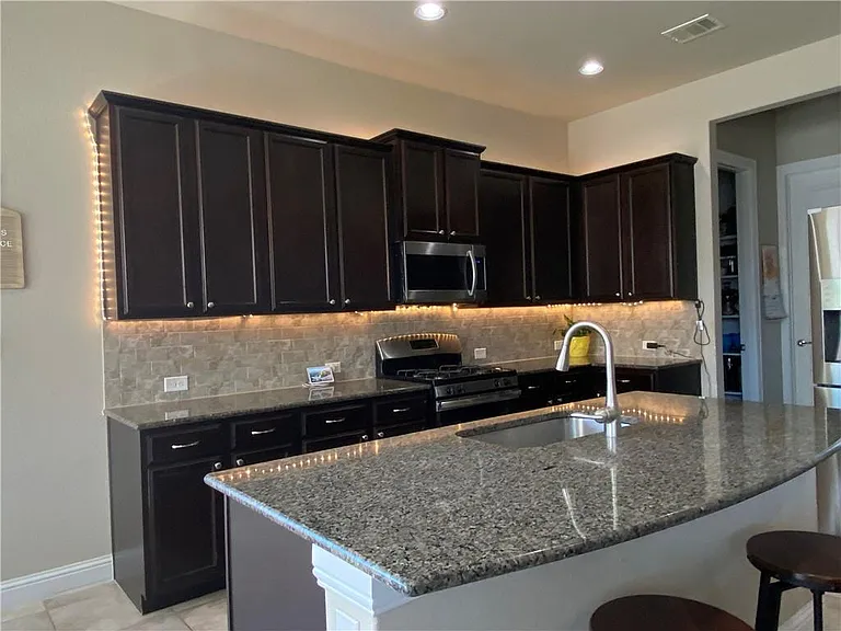 Kitchen with big island, pantry and access to separate Laudnry room and storage area