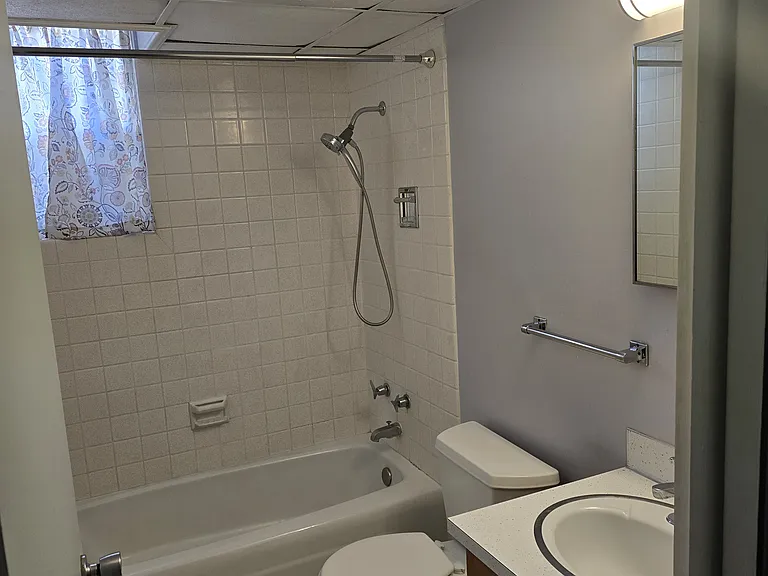 Full size tub and shower in bathroom, ceramic wall and floor tile, storage in vanity and medicine cabinet