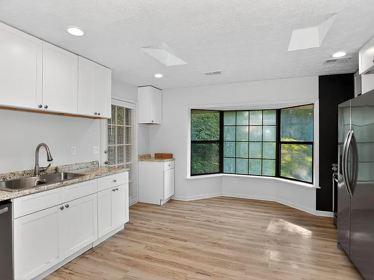 Spacious kitchen with ample cabinetry, granite-look counters, stainless appliances, and a large bay window for dining.