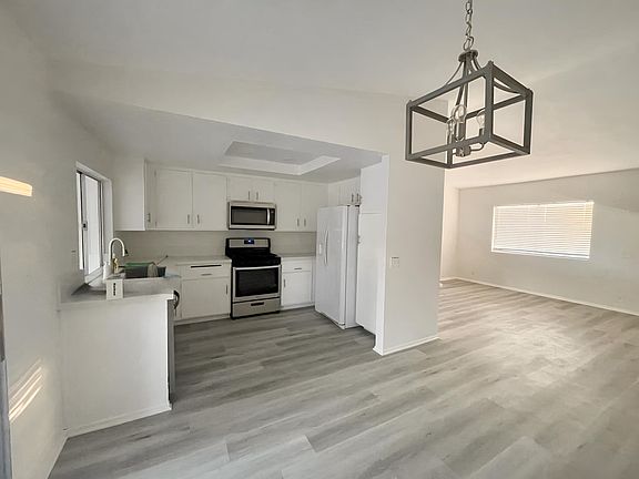 Kitchen features stone countertops, stainless steel appliances, fresh white cabinets.