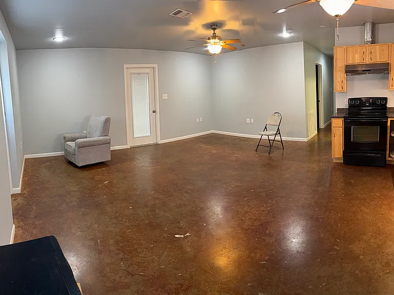 Panoramic view of living area and part of kitchen. Door leads to enclosed parking. Furniture not included.