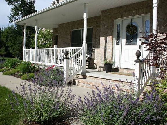 Welcoming wrap-around front porch with perennial gardens.