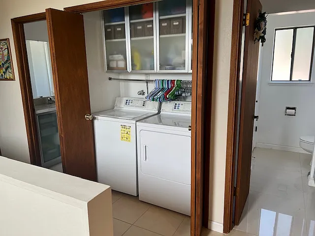 Hallway to washer & dryer, two toilets with sinks, and adjoining shower over Jacuzzi tub behind the washer & dryer.