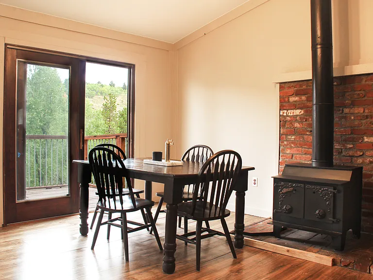 Dining area and sliding doors leading to 750 s.f. of deck overlooking the water with beautiful woodstove, providing a 3rd source of heat (fireplace, wood stove, and central heat)