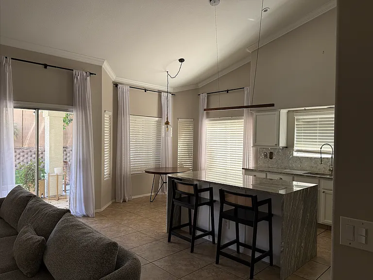 Updated kitchen with waterfall-edge island, stone countertops, and stainless steel appliances.