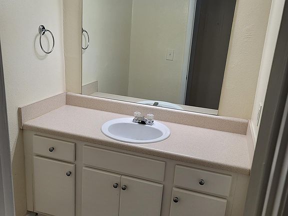 Vanity area with a door that leads to the shower area.