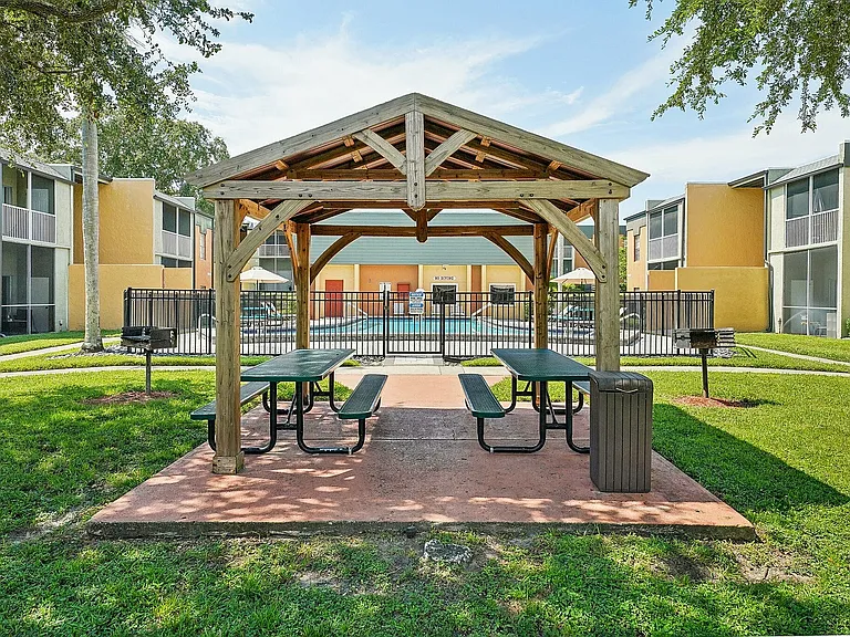 Inviting outdoor space with a charming wooden gazebo, picnic tables, and a view of the pool, perfect for relaxation and gatherings.