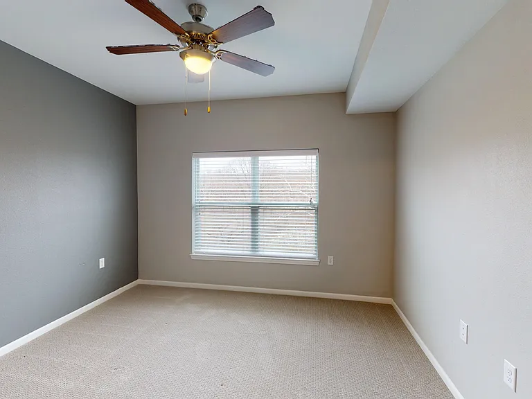 The Hickory's primary bedroom includes a large window, carpet, a ceiling fan and light, and a double door closet. The Hickory's primary bedroom includes a large window, carpet, a ceiling fan and light, and a double door closet.