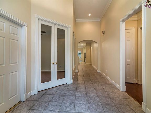 The front entry opens to a gallery hallway with tall ceiling. The French doors on the left open to a study, doorway on right is a hallway to two bedrooms with a jack and jill bath. Study and bedrooms have wood flooring.