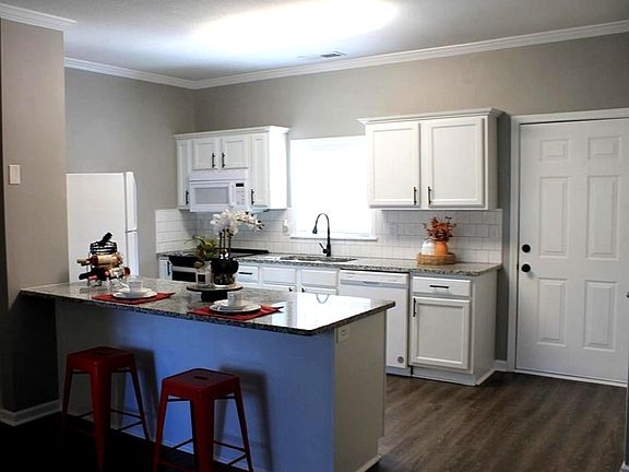 Open concept kitchen with white cabinetry, white appliances, a kitchen bar, and sink