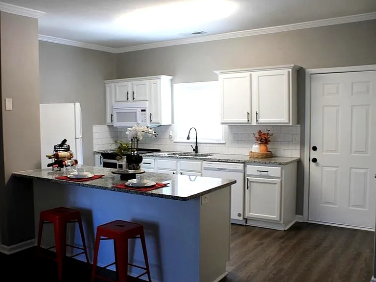 Open concept kitchen with white cabinetry, white appliances, a kitchen bar, and sink