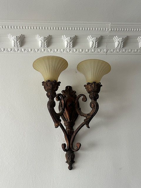 Close-up view of wrought iron wall, sconce, and beautiful crown molding throughout the living room.