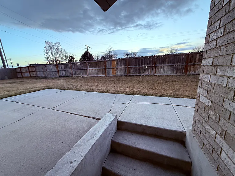 View of steps, patio, and yard, taken from back door.