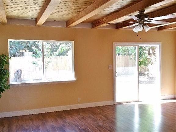Large family room with exposed wood ceiling and fan.