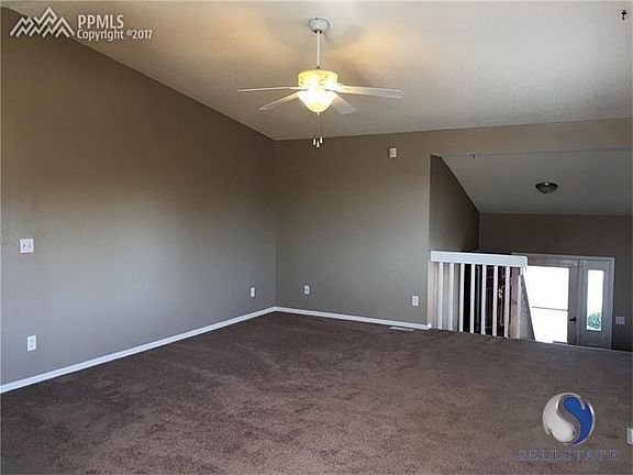 Upper level, roomy living room with vaulted ceilings and ceiling fan.