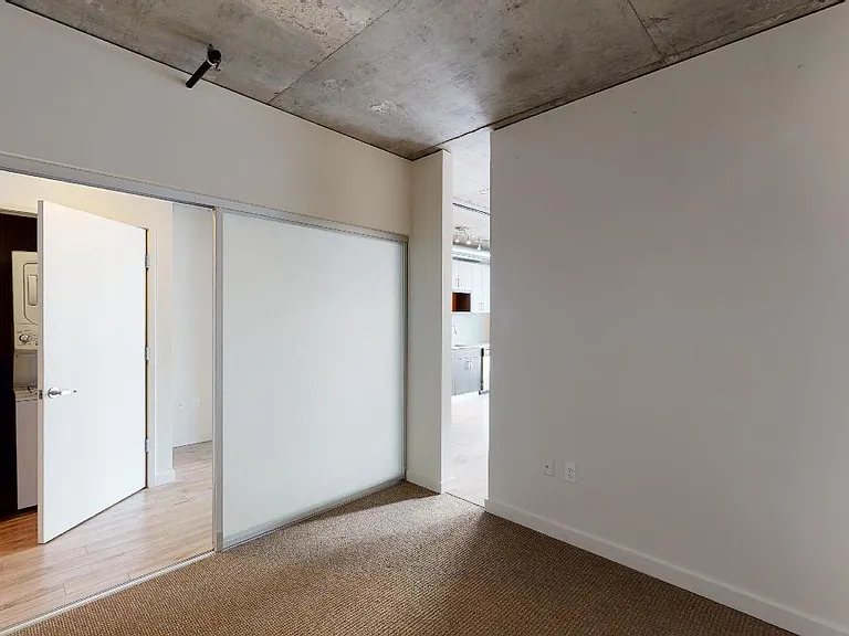 Spacious apartment bedroom with plush carpet flooring.