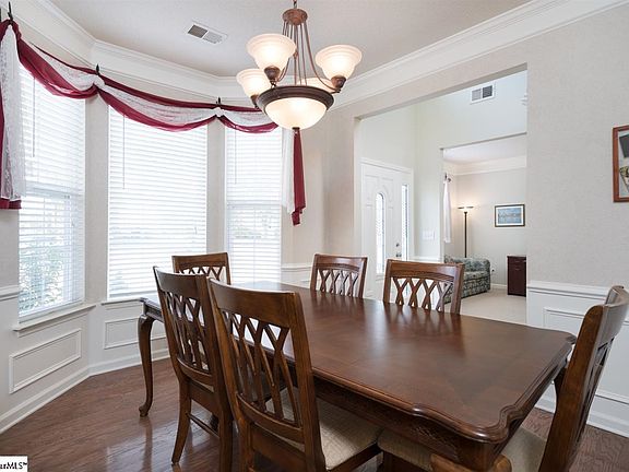 Deep crown molding, wainscoting, gleaming hardwood floors and a large bay window accent this  wonderful dining room