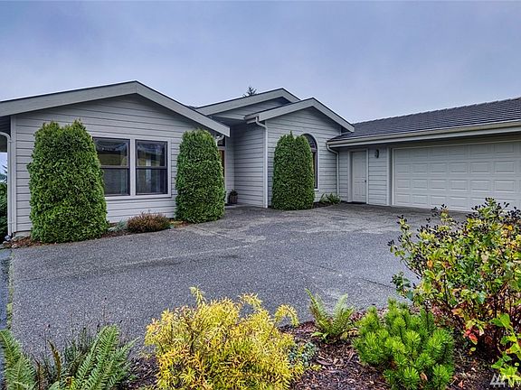 The front of the home faces away from the street.  The left windows are the guest suite.  The right arched window is the dining room.  The door to the right provides entry into the large two-car garage.  