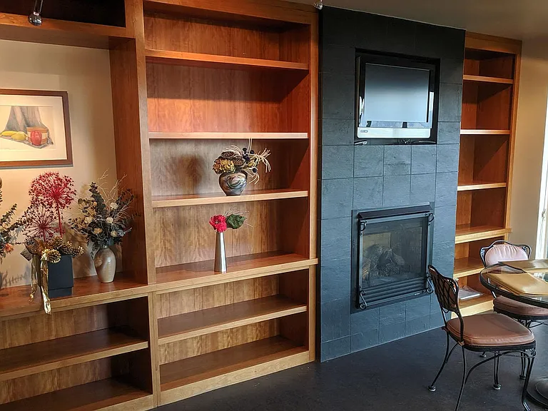 Breakfast room attached to kitchen has built in book shelves, TV, and gas fireplace. Furniture and Art has been removed