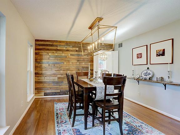 Formal dining room with custom wood pallet wall! And beautiful light fixtures. Hall leads to breakfast room.