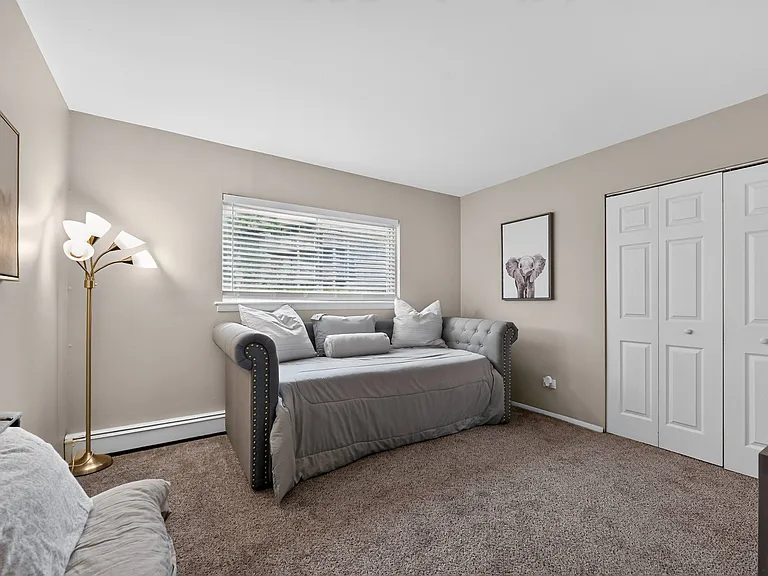 Unwind in a cozy bedroom featuring warm lighting and wall art at Renaissance at Carol Stream in Carol Stream, IL.