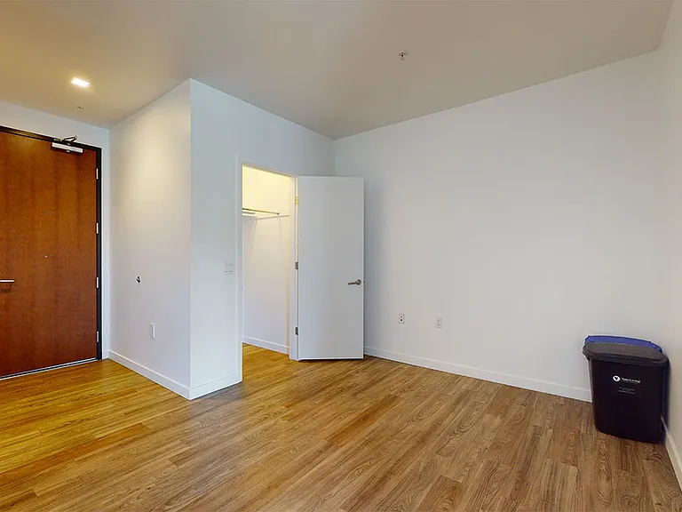 Spacious apartment bedroom with large closet and wood-style or concrete flooring.