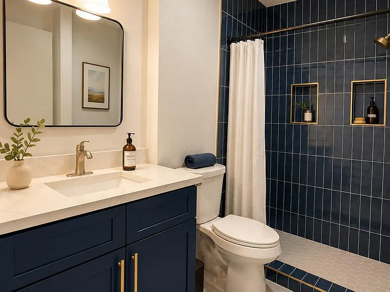 Updated full bath with navy vanity, quartz-style countertop, framed mirror, and tiled tub/shower with built-in niches.