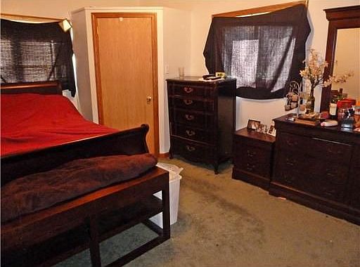 This bedroom has neutral decor and two windows with plenty of natural light