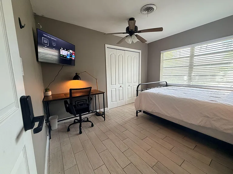 Private bedroom, large window with blinds, spacious closet, ceiling fan, and a dedicated work desk.