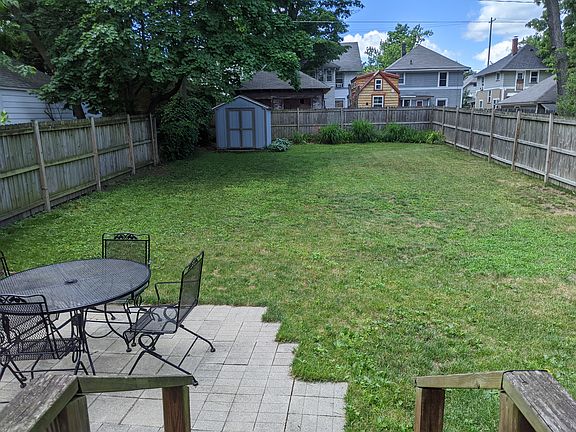 A large fenced in backyard features a patio and space for gardening.
