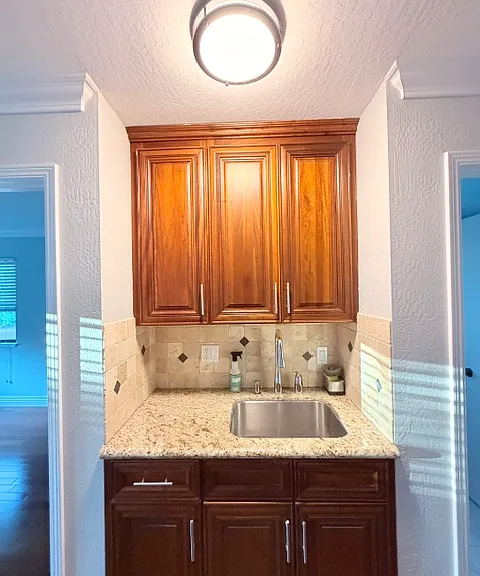 Kitchen sink with pull-down faucet and garbage disposal. Bedroom to the left and bathroom to the right.