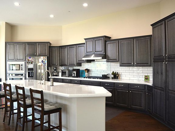 Kitchen has oversized islands, quartz countertops, KitchenAid appliances, upgraded cabinetry, water osmosis, glass cover behind stove, liner in all cabinets and drawers.