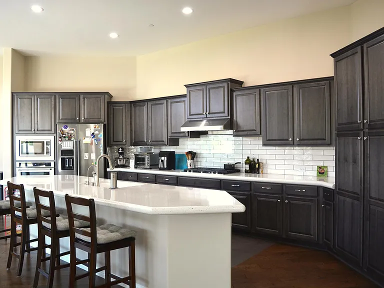 Kitchen has oversized islands, quartz countertops, KitchenAid appliances, upgraded cabinetry, water osmosis, glass cover behind stove, liner in all cabinets and drawers.