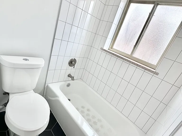 Modern bathroom featuring a sleek white bathtub, elegant geometric floor tiles, and a bright window for natural light. Modern bathroom featuring a sleek white bathtub, elegant geometric floor tiles, and a bright window for natural light.