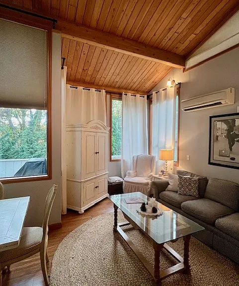 Another view as you enter the unit, looking in to main living area and out to the rear deck, beyond which lies trees for privacy from road. Adjust temperature to your liking w/ wall-mounted, individually controlled AC/Heat unit.
