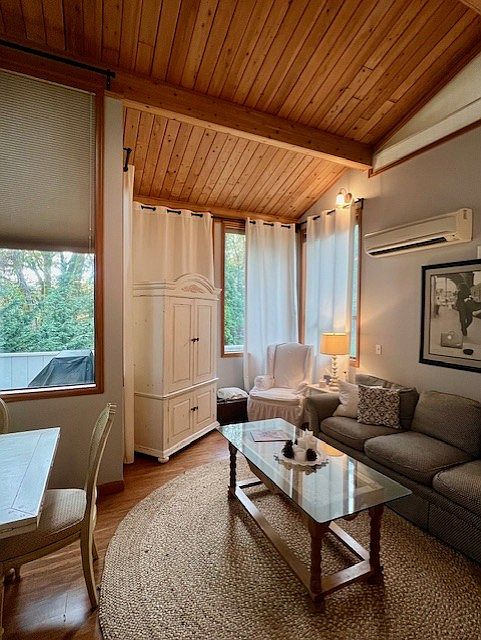 Another view as you enter the unit, looking in to main living area and out to the rear deck, beyond which lies trees for privacy from road. Adjust temperature to your liking w/ wall-mounted, individually controlled AC/Heat unit.