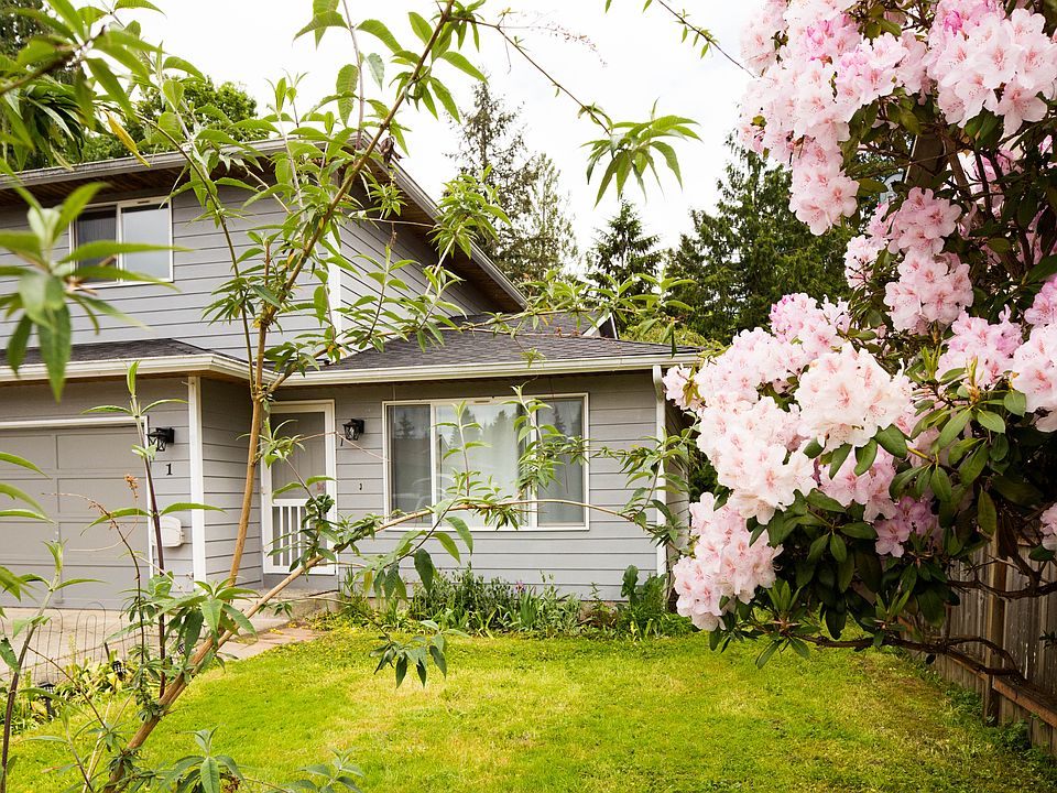 Front yard and exterior surrounded by mature landscaping and flowering trees, creating a peaceful and private residential setting.