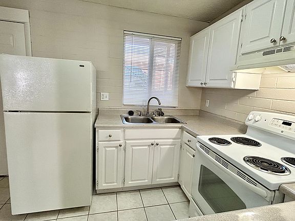 Bright and inviting kitchen with modern white cabinets, sleek countertops, and an efficient electric stove.