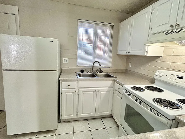 Bright and inviting kitchen with modern white cabinets, sleek countertops, and an efficient electric stove.