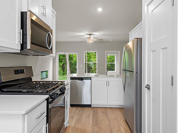 The kitchen has stainless steel appliances and plank flooring.