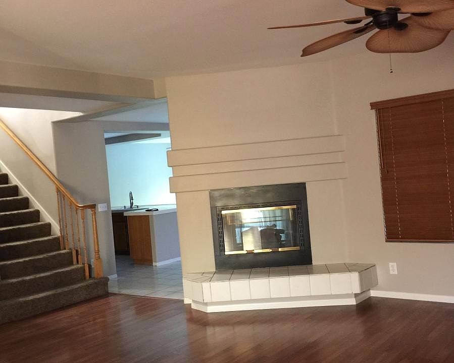 Living room with gas two-sided fireplace and ceiling fan.