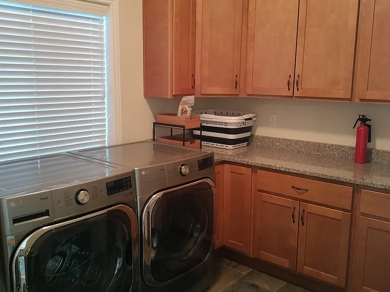 Laundry room with new LG washer/dryer (20+ settings), ample counters, and cabinets for organization. Conveniently located by the garage, with benches, a coat rack, and a half bath_perfect for managing outdoor gear and storage needs.