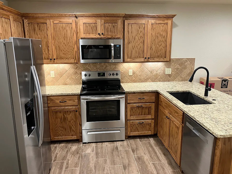 Beautiful, stained oak cabinets, stainless steel appliances and lighted tumbled stone backsplash.