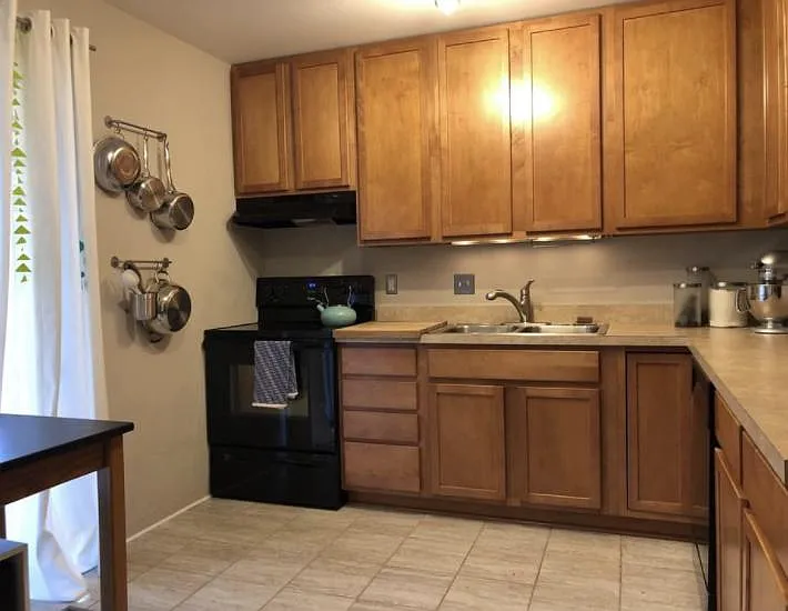 Kitchen has porcelain floors, solid wood cabinets, and a door wall (sliding door) facing the front of property. Includes refrigerator, dishwasher and new electric stove.