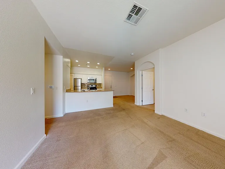 Gourmet kitchen with stainless steel appliances, dining and living room with plush carpet flooring.