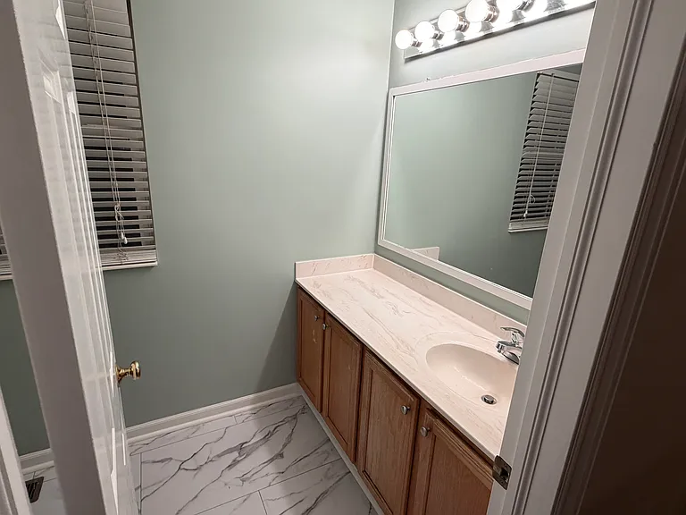 Hallway bath with single vanity and large mirror.