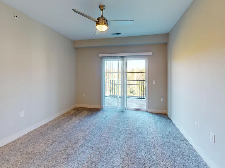 The Dogwood living room features lush carpeting, a ceiling fan, and a sliding glass door to a private patio or balcony. The Dogwood living room features lush carpeting, a ceiling fan, and a sliding glass door to a private patio or balcony.