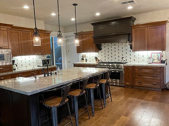 Open design chef's kitchen with 6 burner Thermador range with griddle, side by side oversize refrigerator and farm sink.