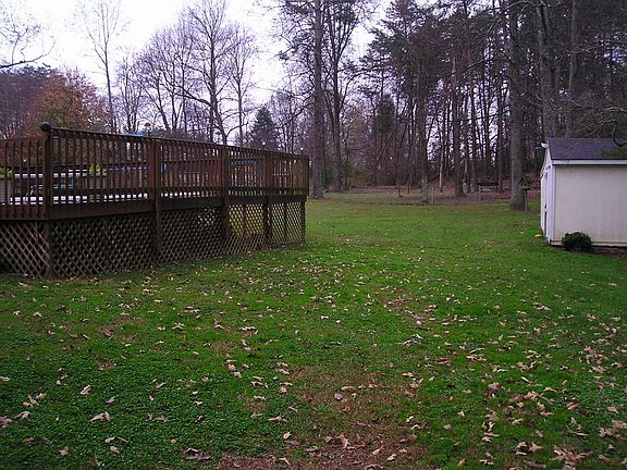 big fenced in back yard with storage building